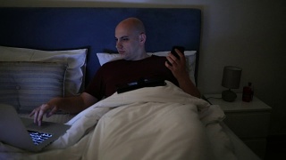 疲惫的秃顶男人在床上工作视频素材模板下载