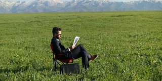 一位商人坐在田野里的办公椅上