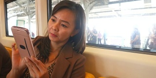 商务女性在城市火车上使用智能手机