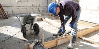 工人用泥铲将混凝土放入模板中。