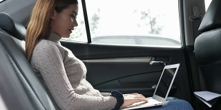 年轻女子在车里用笔记本电脑打字