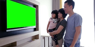 父母和女儿看Chromakey电视
