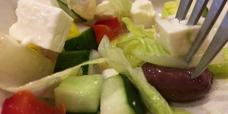 用叉子吃希腊沙拉，橄榄，生菜，黄瓜，奶酪，西红柿