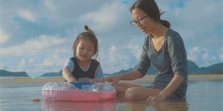 亚洲年轻母亲和小女儿在海滩上玩耍