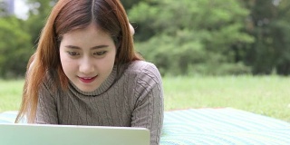 快乐的女学生带着笔记本电脑在公园里，摄影车拍摄
