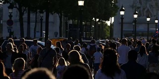 游客们在傍晚的阳光下漫步在香榭丽舍大街上