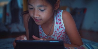 可爱的小女孩使用平板电脑在晚上，特写