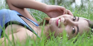 年轻女子躺在公园的草地上听音乐