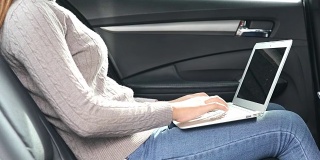 女性在汽车的副驾驶座上使用智能手机