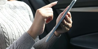 近距离观察亚洲女性在车里使用平板智能手机