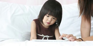 亚洲宝宝在家里和妈妈一起使用平板电脑