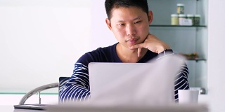 摄影:在家庭办公室使用笔记本电脑的男人