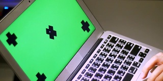 晚上在家庭办公室用绿色屏幕的笔记本电脑敲击键盘