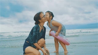 女孩在海滩上亲吻妈妈的脸颊视频素材模板下载
