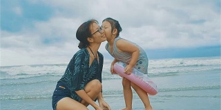 女孩在海滩上亲吻妈妈的脸颊
