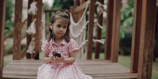 一个小女孩坐在泰国的公园里，戴着耳机听播客