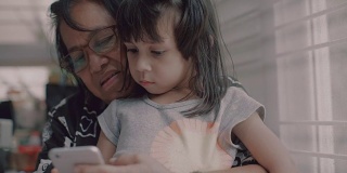 年轻女孩和老年妇女使用智能手机。泰国