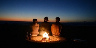 朋友们在海滩篝火边看日落