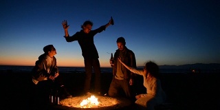 朋友们在海滩篝火上喝啤酒