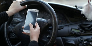 正面视图的现代智能手机与空白的白色屏幕与复制空间为您的文本或设计，近距离司机的手在汽车中使用手机