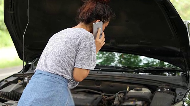 亚洲妇女在看手机和压力妇女后，汽车抛锚在街上