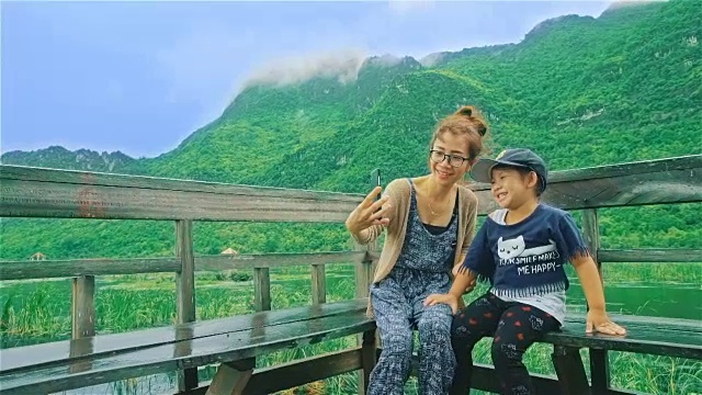 Mother and daughter relaxing under the rain and taking selfie in the nature