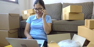 年轻的亚洲女性查看电子邮件收件箱，并使用电话从客户那里获取订单