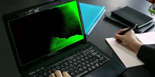商务人员在办公室使用绿色屏幕的笔记本电脑作为色键并在笔记本上写字