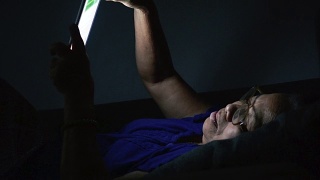 老年妇女晚上使用平板电脑视频素材模板下载