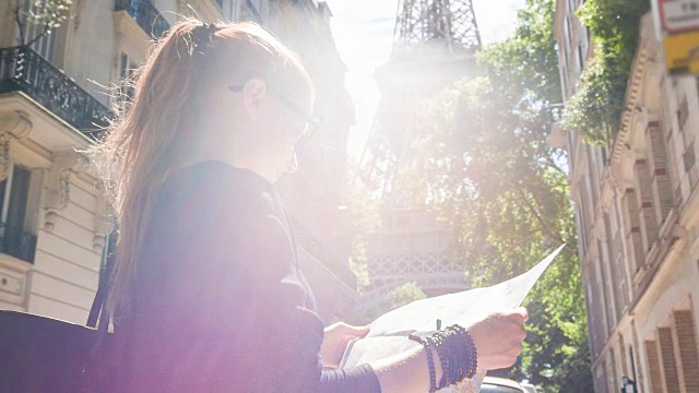 游客拿着巴黎地图，站在一条小巷里看埃菲尔铁塔