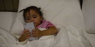 4k移动洋娃娃:孩子们在床上玩手机游戏