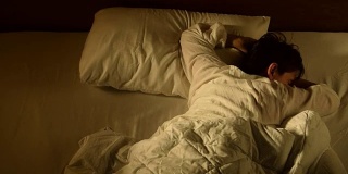 一名抑郁的女子因失眠躺在床上的镜头，快速移动