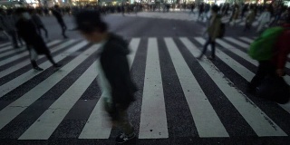 一群人在夜晚穿过日本涩谷市的街道