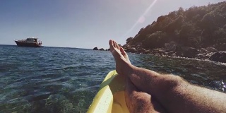 一个男人在夏天的海上的皮划艇上放松