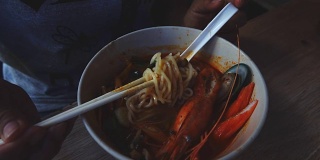 慢镜头:女子吃海鲜辣味面汤。