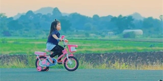 在乡下骑自行车的亚洲小女孩
