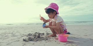 可爱的女孩在沙滩上玩沙子和快乐