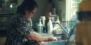 老女人在家里洗碗