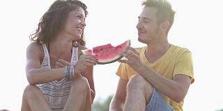 年轻夫妇在海滩上吃西瓜