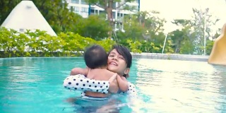 年轻的母亲教儿子如何在游泳池游泳。/泰国。