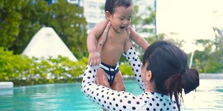 一个小男孩和妈妈在游泳池里玩耍和游泳