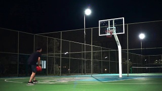 运动概念:一个人晚上独自在室外打篮球。视频素材模板下载