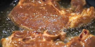 色彩斑斓:多汁的猪肉排在煎锅里煎。