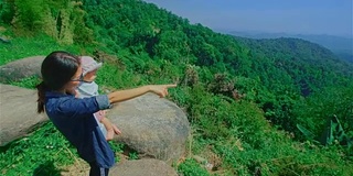 母女俩站在山顶，眺望美丽的景色