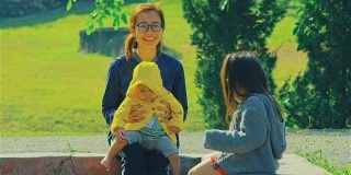 年轻的母亲和两个女儿在公园里玩
