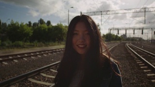 亚洲年轻女子在铁路上倒退。视频素材模板下载