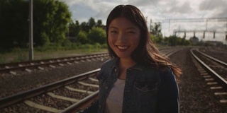 害羞的亚洲年轻女子独自在铁路上。