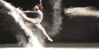 美丽的芭蕾舞者在一个旋转与粉雪在工作室。慢动作