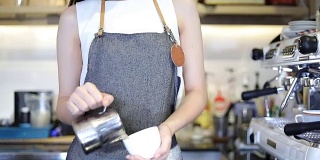 亚洲妇女咖啡师微笑和拿着咖啡杯和使用机器在咖啡店柜台-工作妇女小企业主食品和饮料的咖啡馆概念