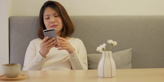 一个女人在咖啡厅休息，在沙发上用她的智能手机，多莉从右向左射击